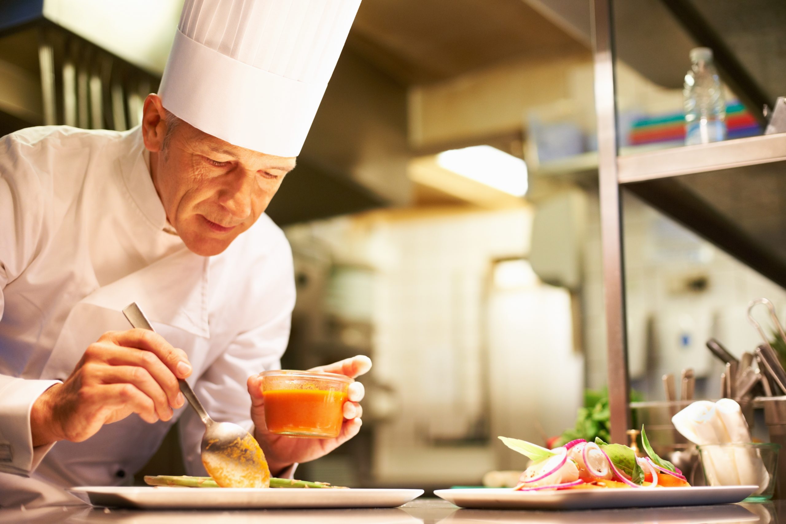 Experienced chef preparing a delicious meal for customers in his commercial kitchen